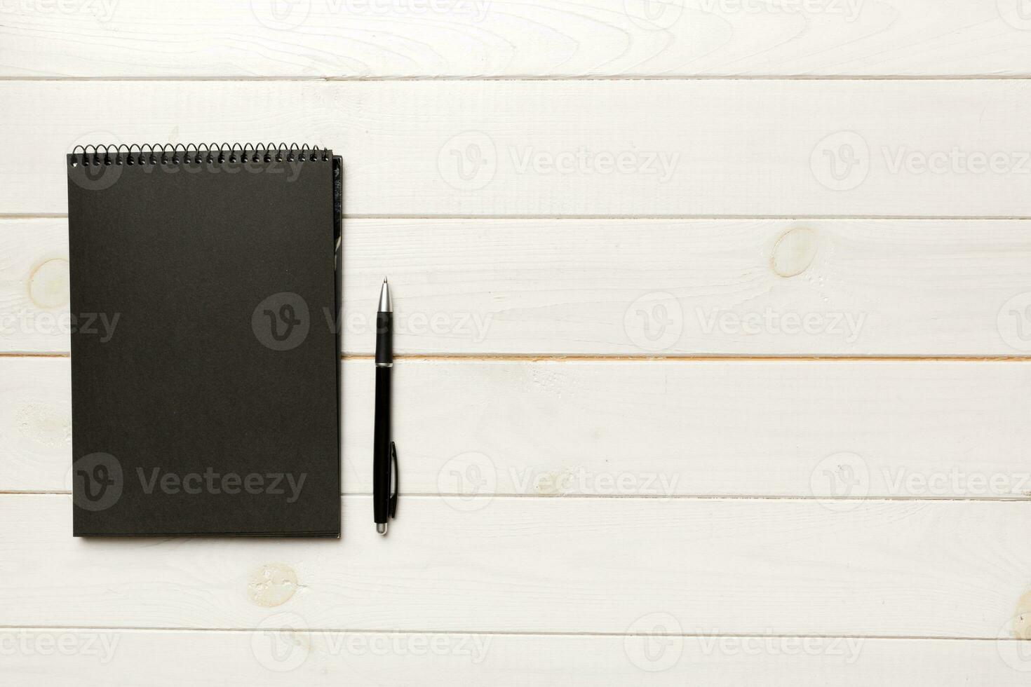colegio cuaderno en un de colores fondo, espiral negro bloc en un mesa parte superior ver foto