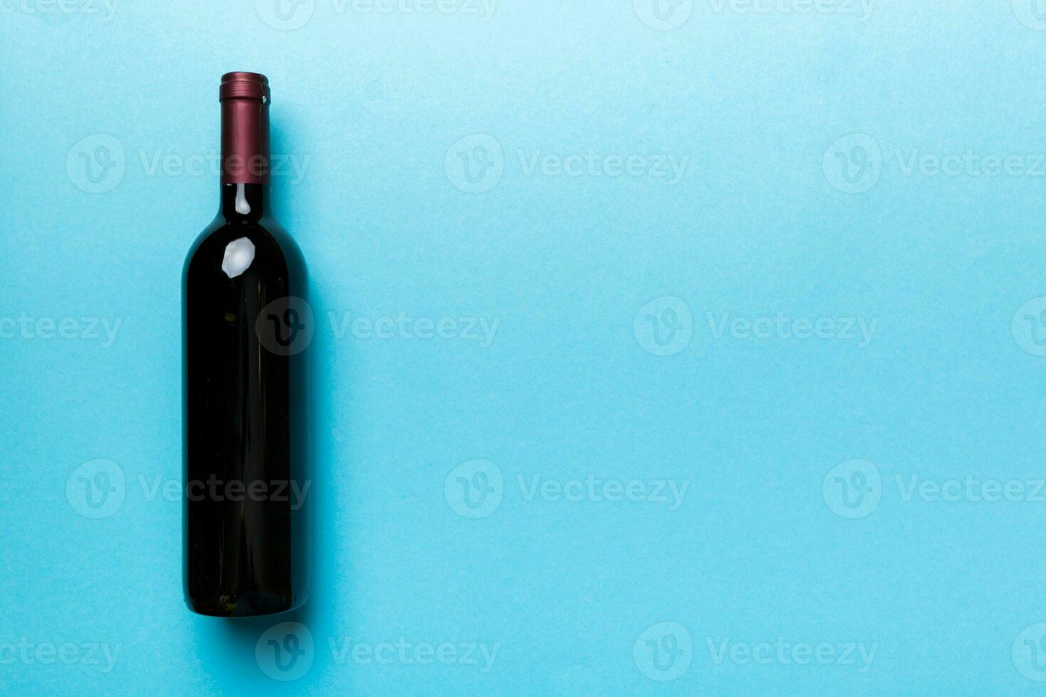 One Bottle of red wine on colored table. Flat lay, top view wth copy space photo