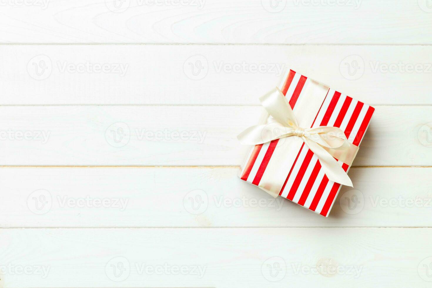 Beautiful gift box with a colored bow on the white wooden table. Top view banner with copy space for you design photo
