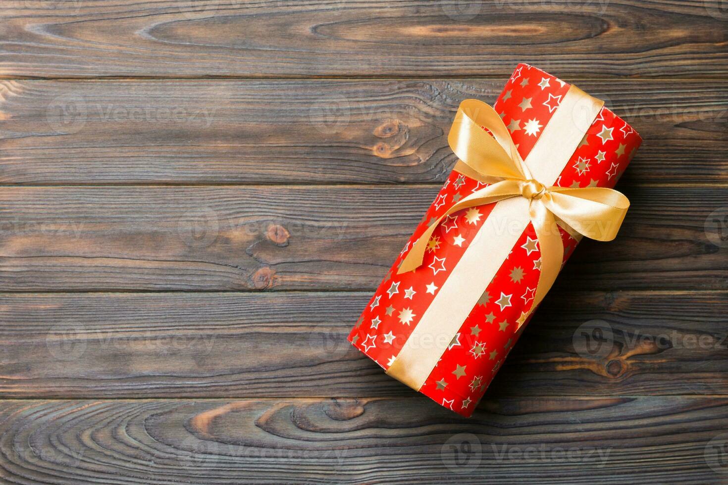 Beautiful gift box with a gold bow on the dark wooden table. Top view banner with copy space for you design photo