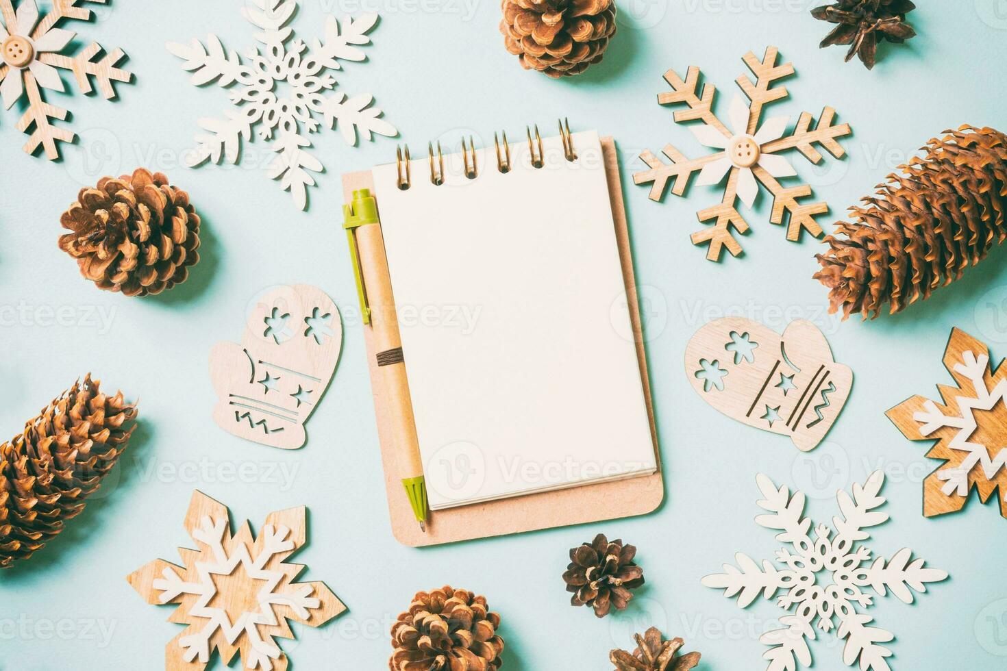 vista superior del cuaderno, juguetes navideños y decoraciones sobre fondo azul de navidad. concepto de tiempo de año nuevo foto