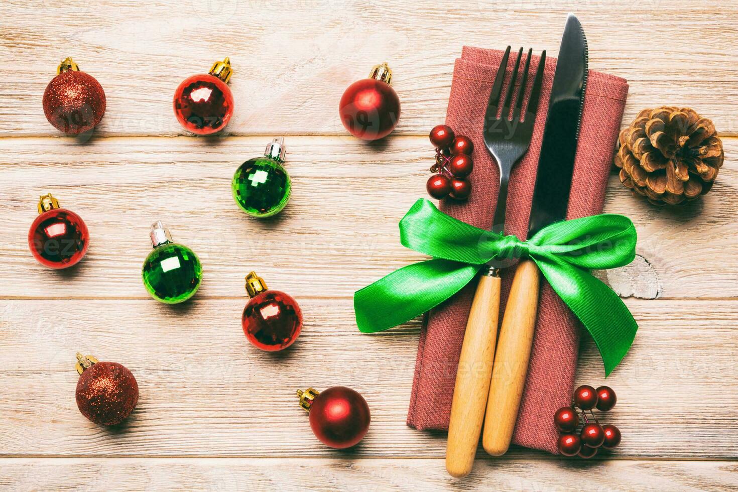 Top view of holiday set of fork and knife on wooden background. Close up of Christmas decorations and toys. New Year Eve concept photo