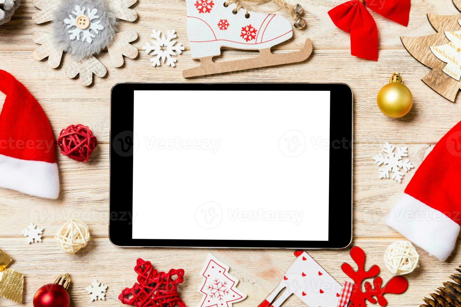 Top view of tablet on holiday wooden background. New Year decorations and toys. Christmas concept photo