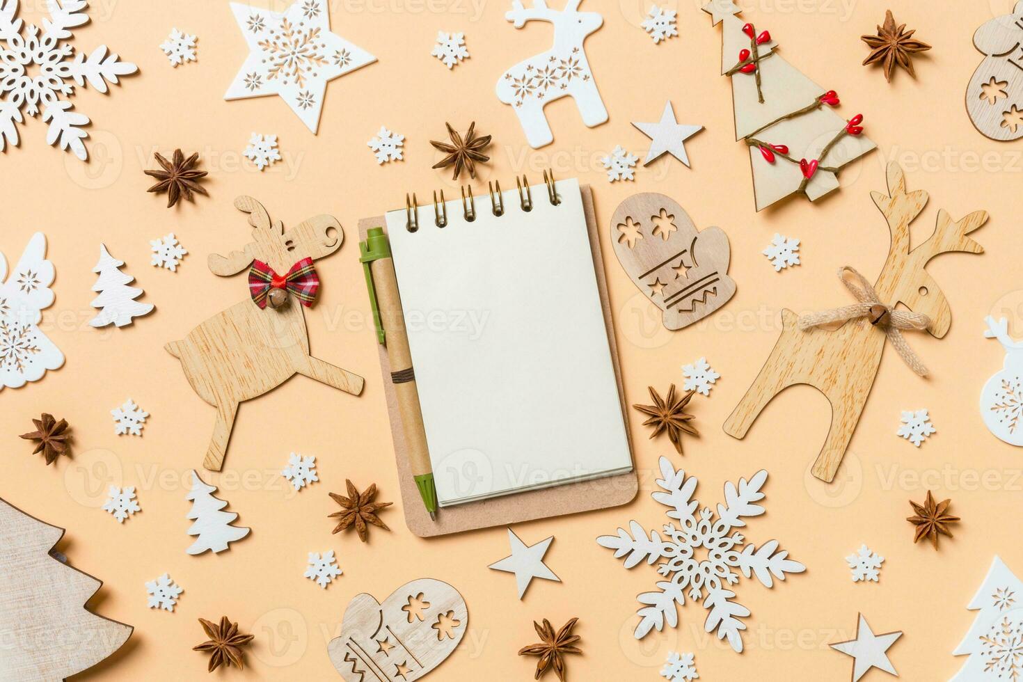 Festive decorations and toys on orange background. Top view of notebook. Merry Christmas concept photo