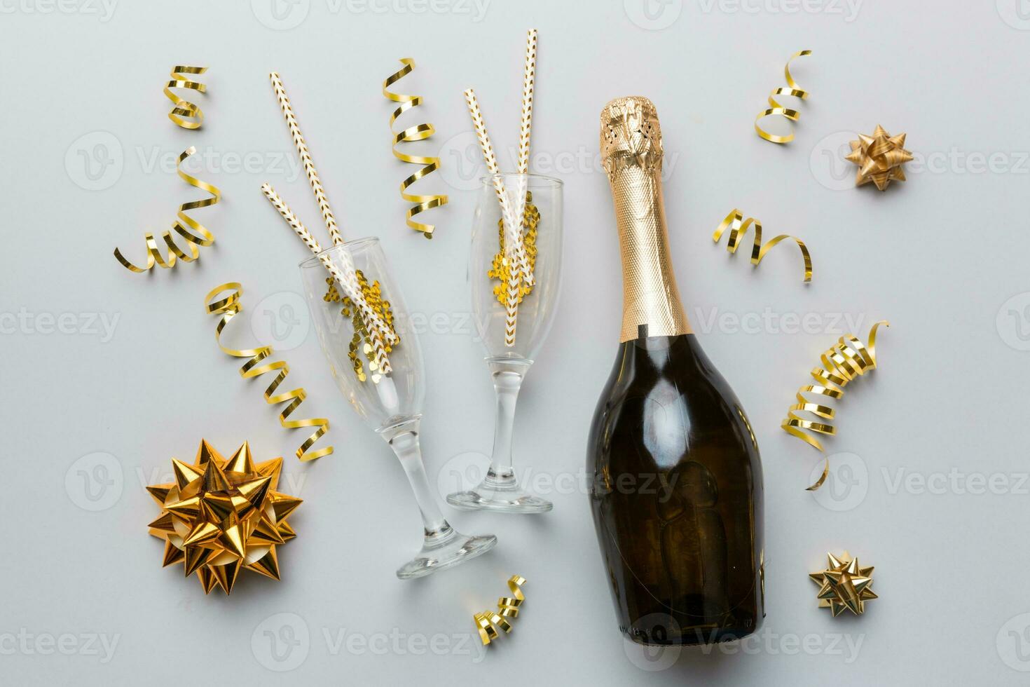 bottle of champagne with glasses and colorful confetti on colored background. top view flay lay photo