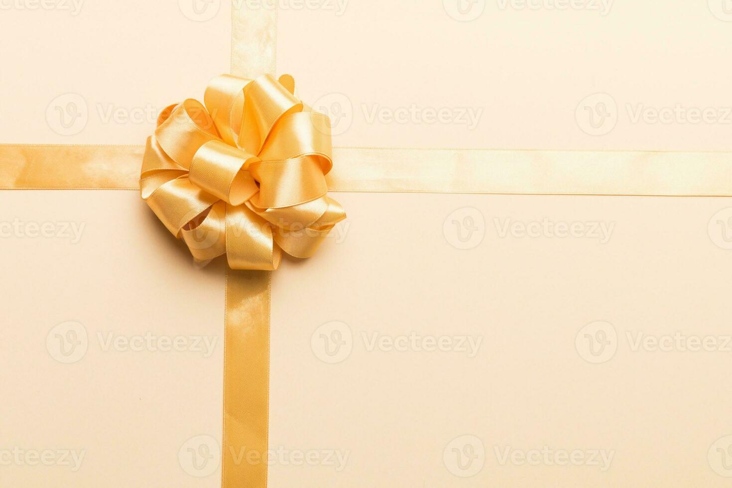 Top view of gold ribbon rolled and yellowbow isolated on colored background. Flat lay with copy space photo