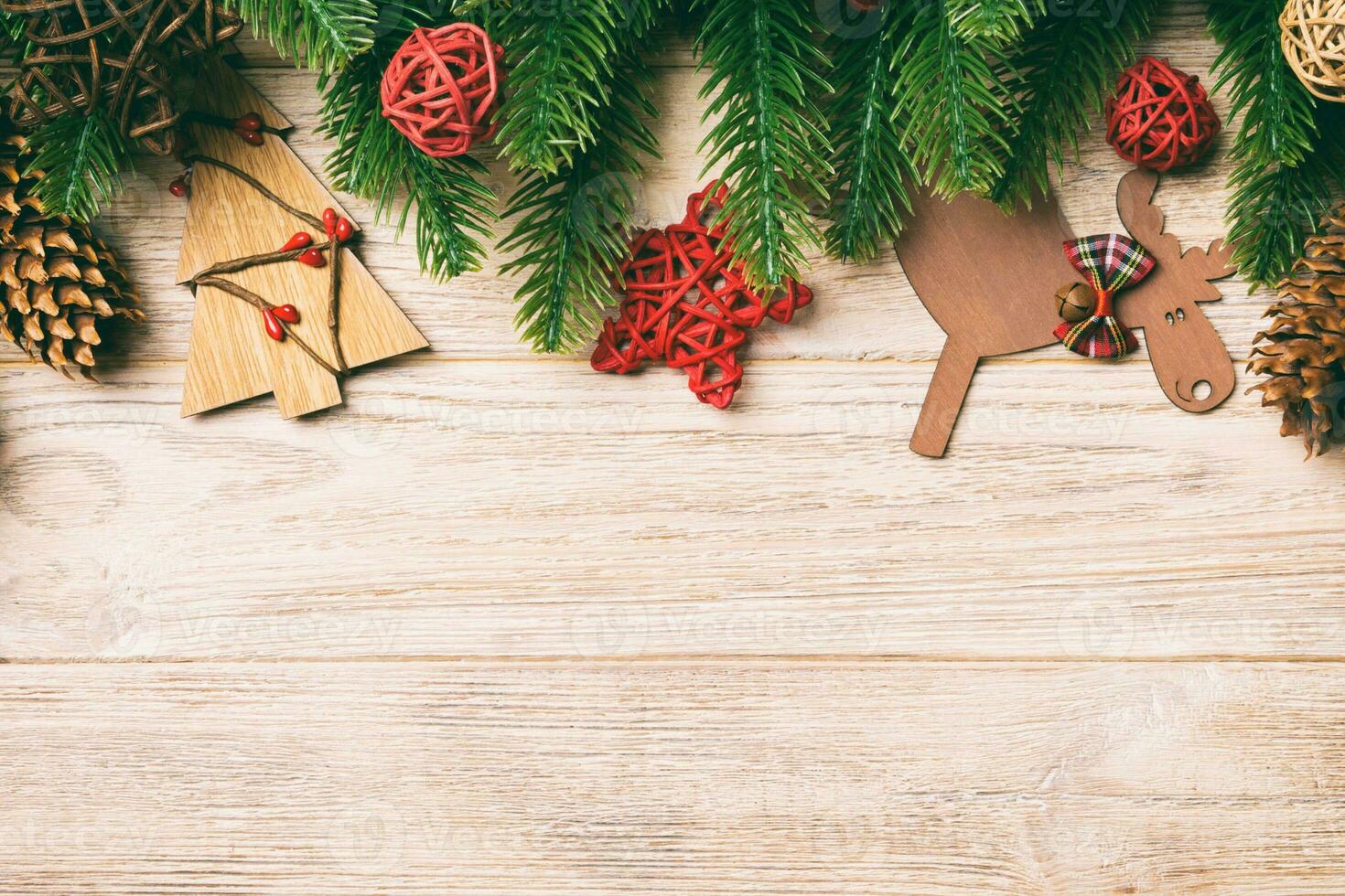 Top view of Christmas toys, decorations and fir tree branches on wooden background. New Year holiday concept with copy space photo