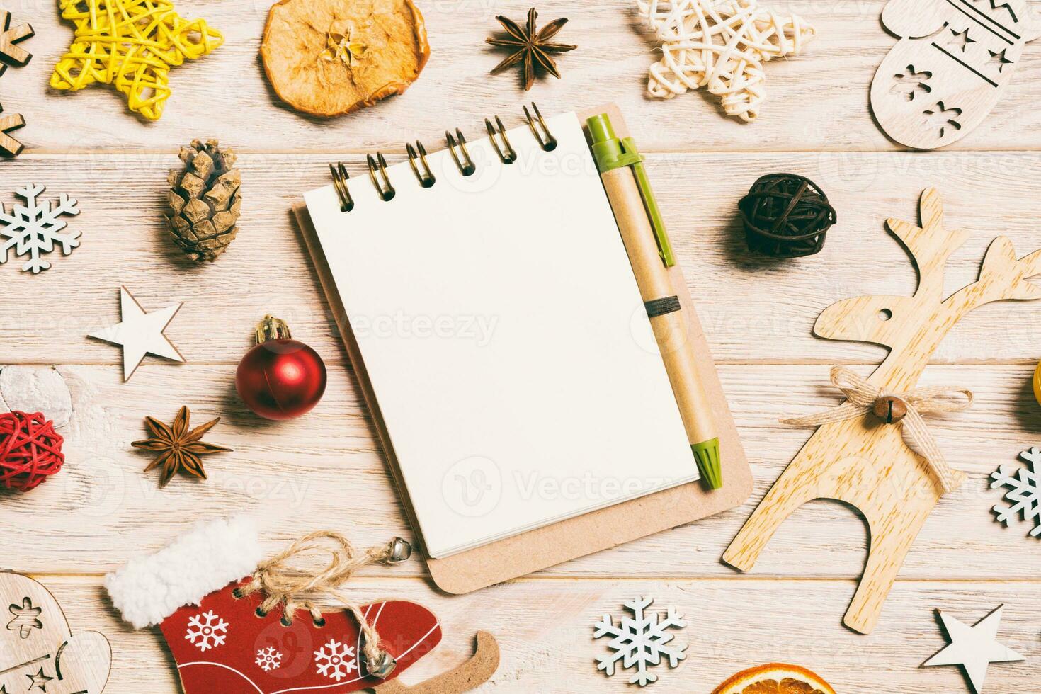 Top view of notebook on wooden background made of Christmas decorations. New Year concept photo