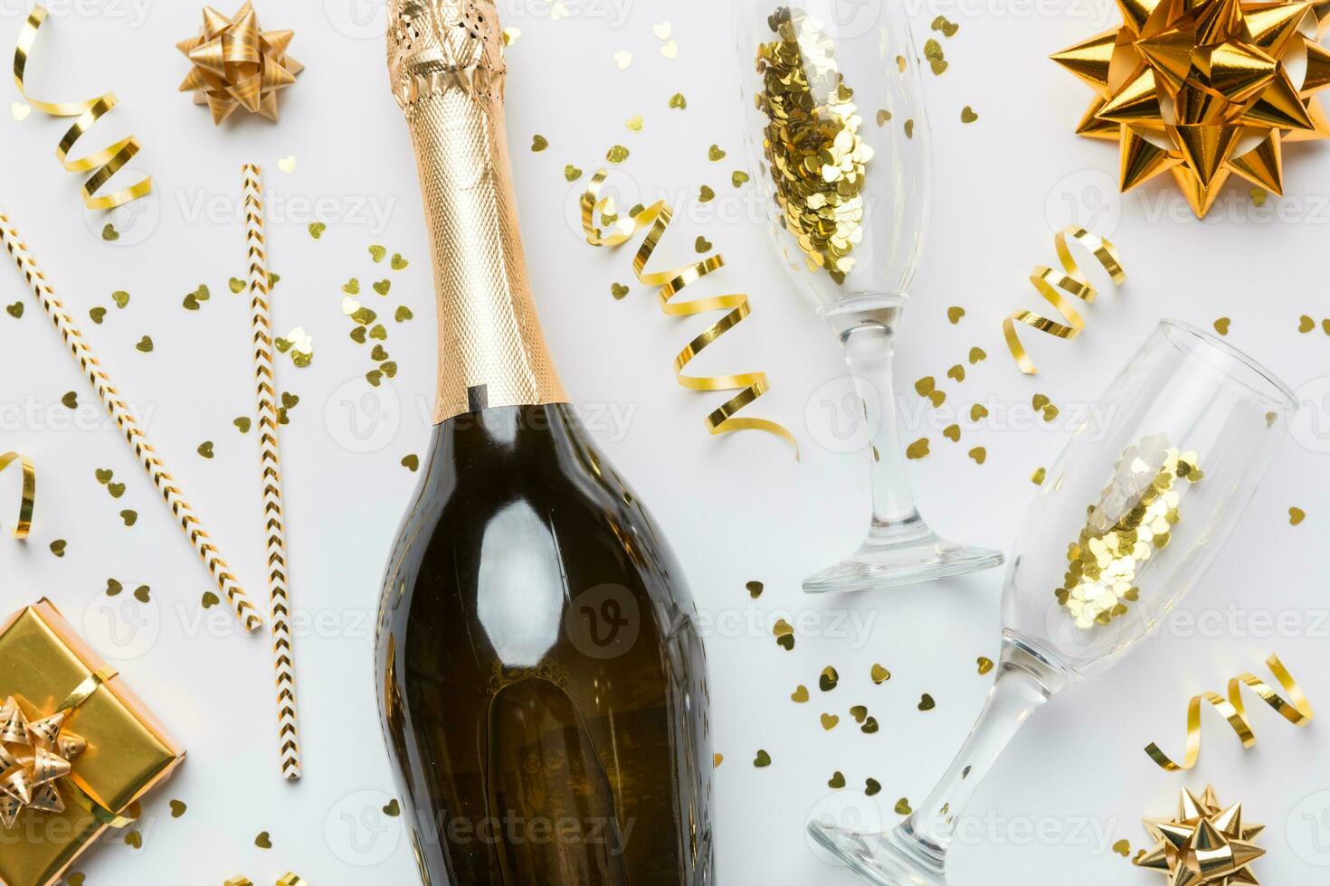 Bottle of champagne with colored glitter, confetti and gift box space for text on colorfull background, top view. Hilarious, christmas and birthday celebration photo