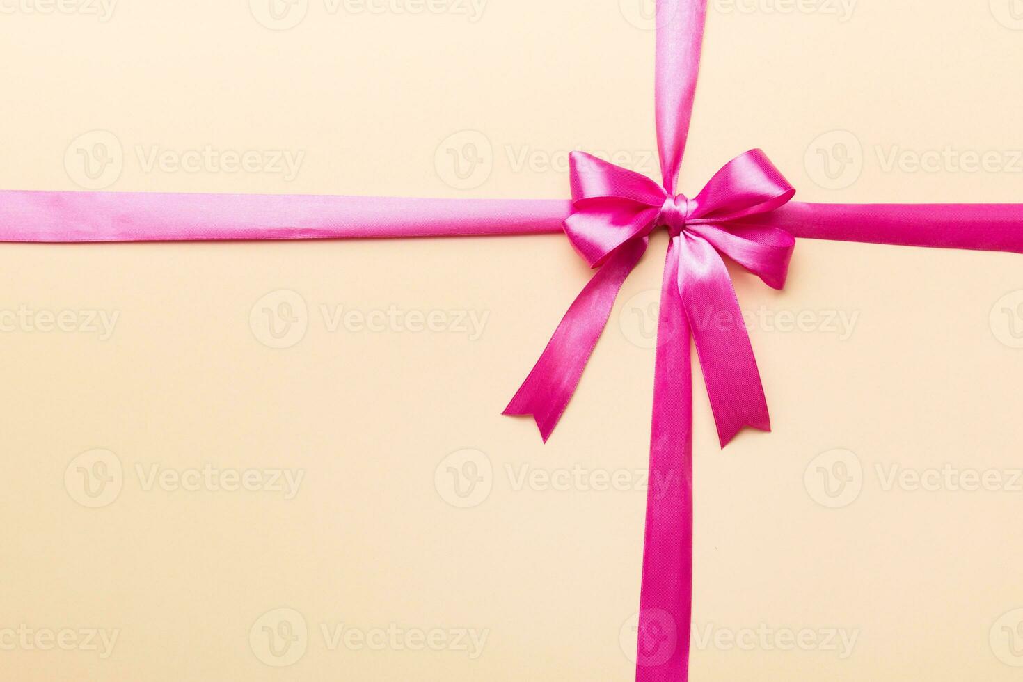 Top view of purple ribbon rolled and pink bow isolated on colored background. Flat lay with copy space photo