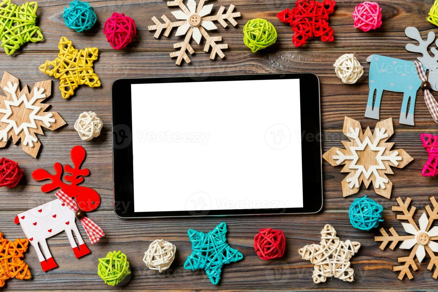 Top view of tablet on holiday wooden background. New Year decorations and toys. Christmas concept photo