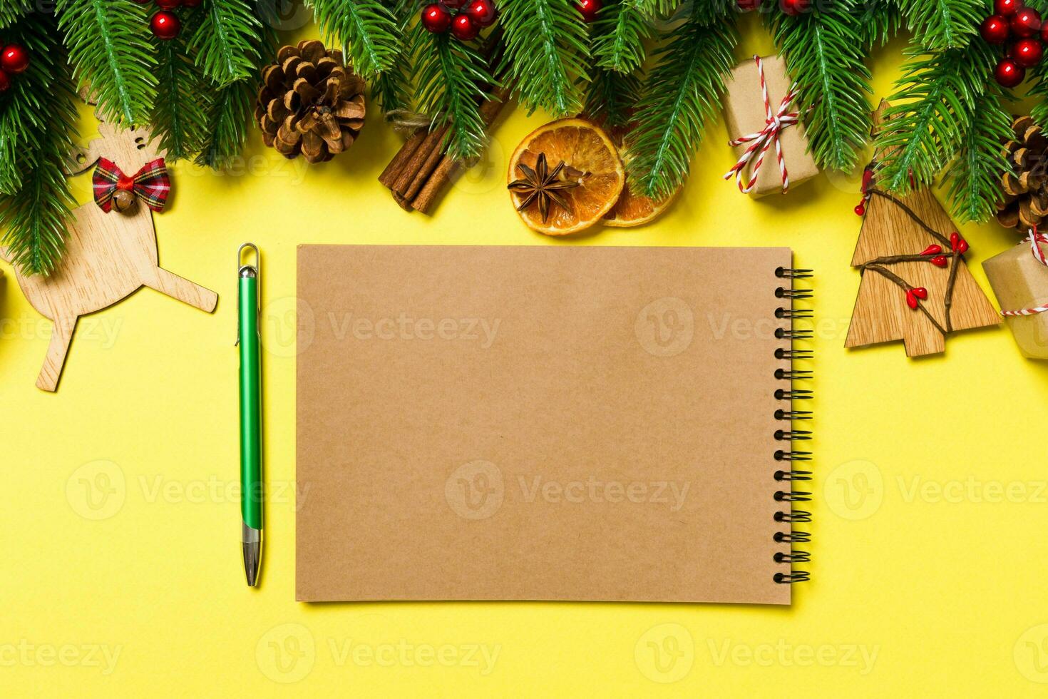 Top view of notebook on yellow background made of Christmas decorations. New Year time concept photo