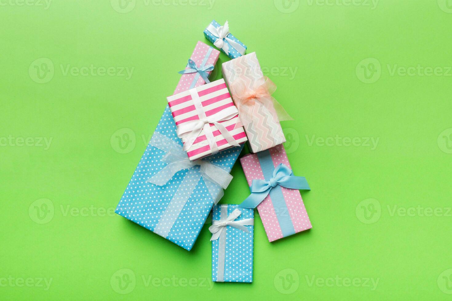 Christmas tree made of beautifuly wrapped presents on colored background, view from above. New Year gift box minimal concept with copy space photo