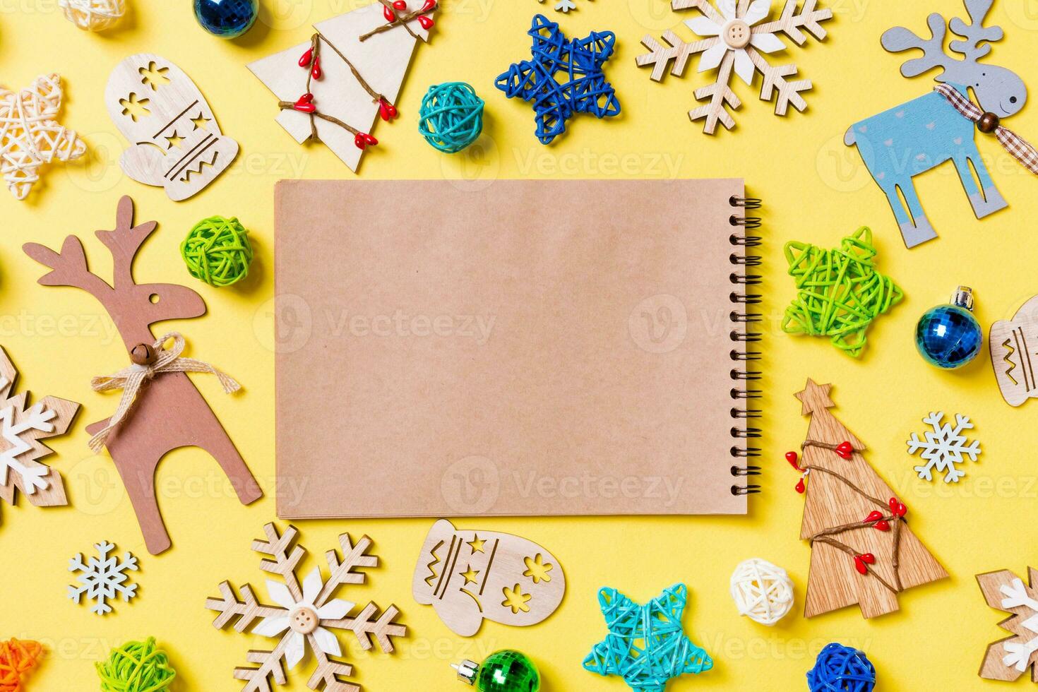 Top view of notebook on yellow background with New Year toys and decorations. Christmas time concept photo