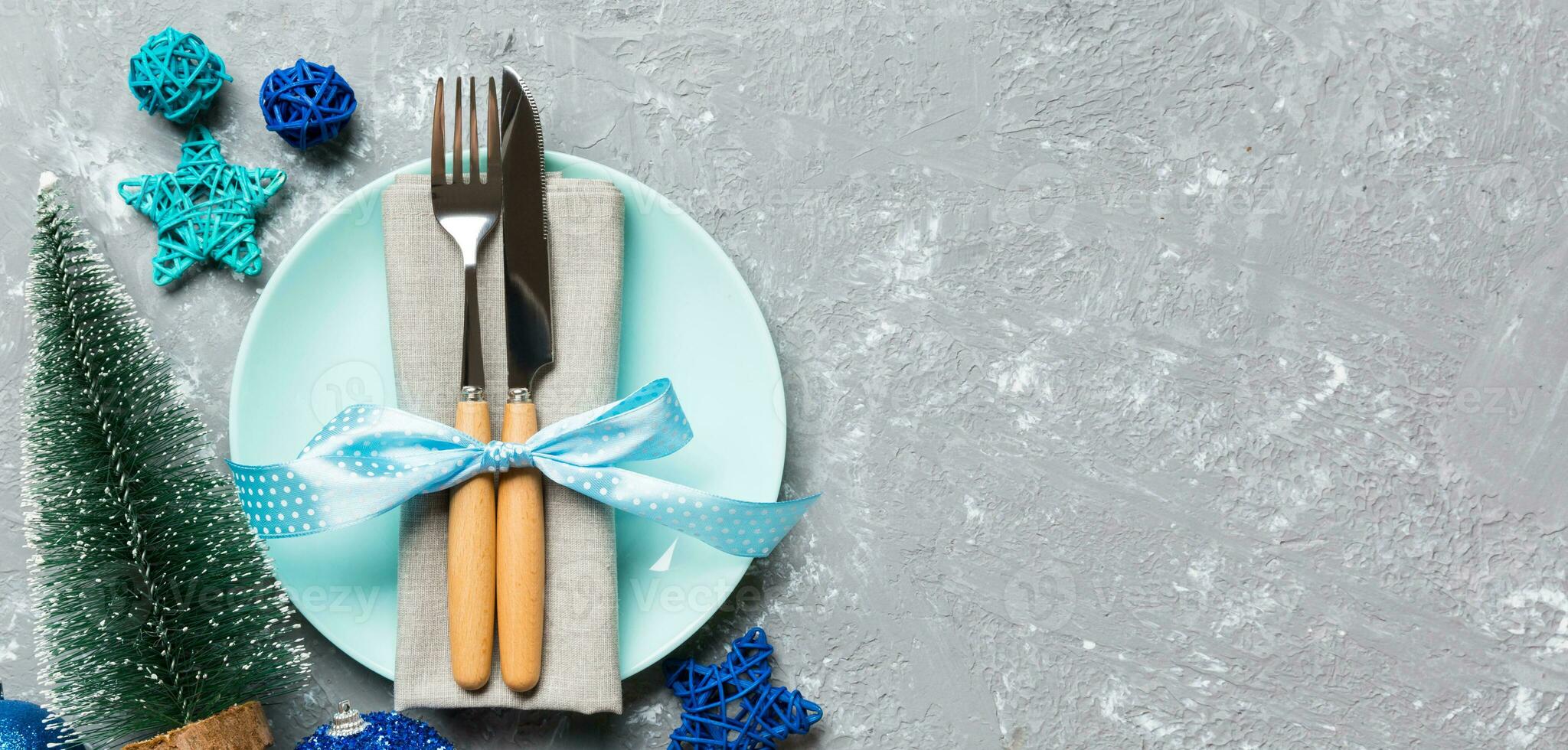 Holiday composition of Christmas dinner on cement background. Top view of plate, utensil and festive decorations. New Year Advent concept with copy space photo