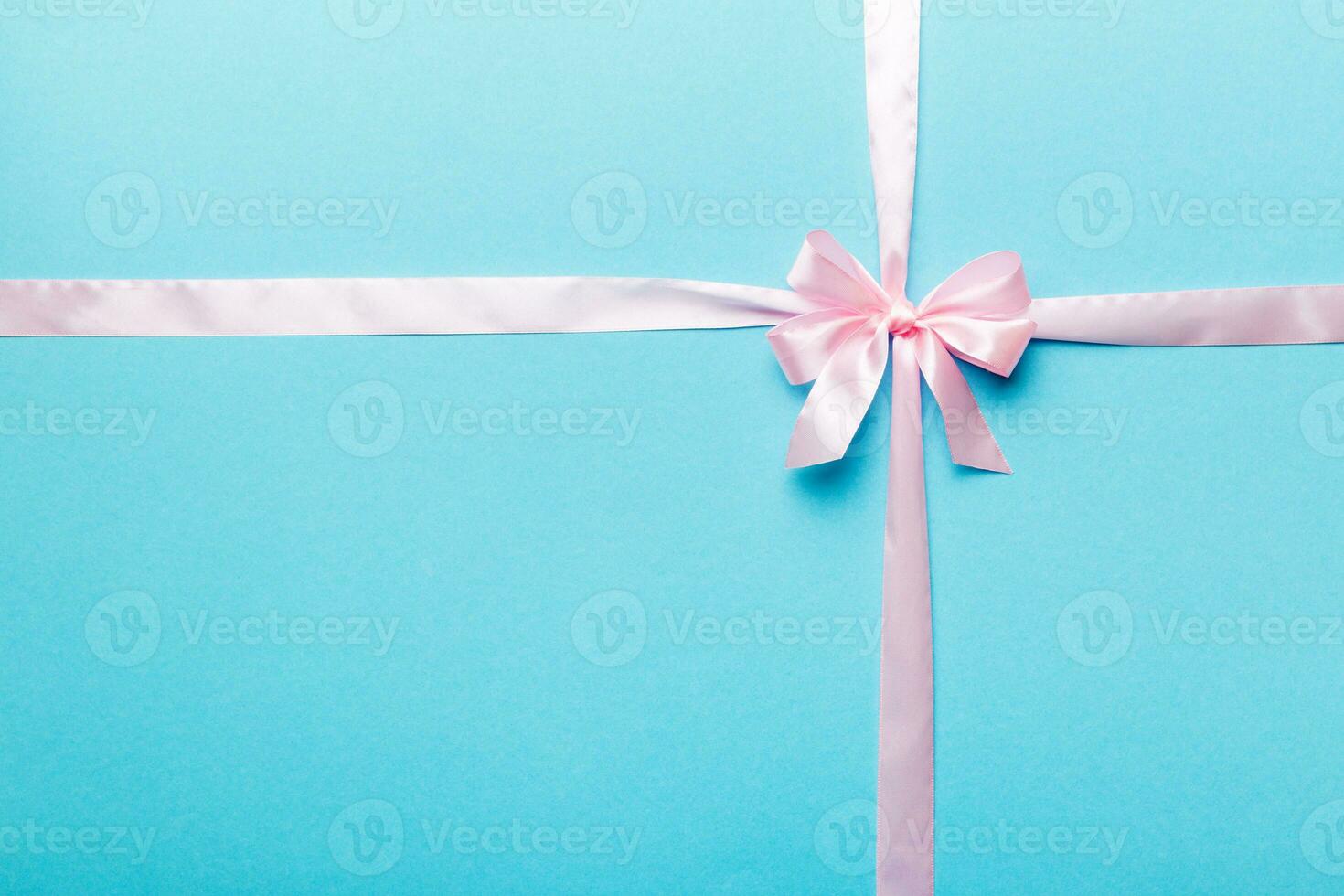 Top view of purple ribbon rolled and pink bow isolated on colored background. Flat lay with copy space photo