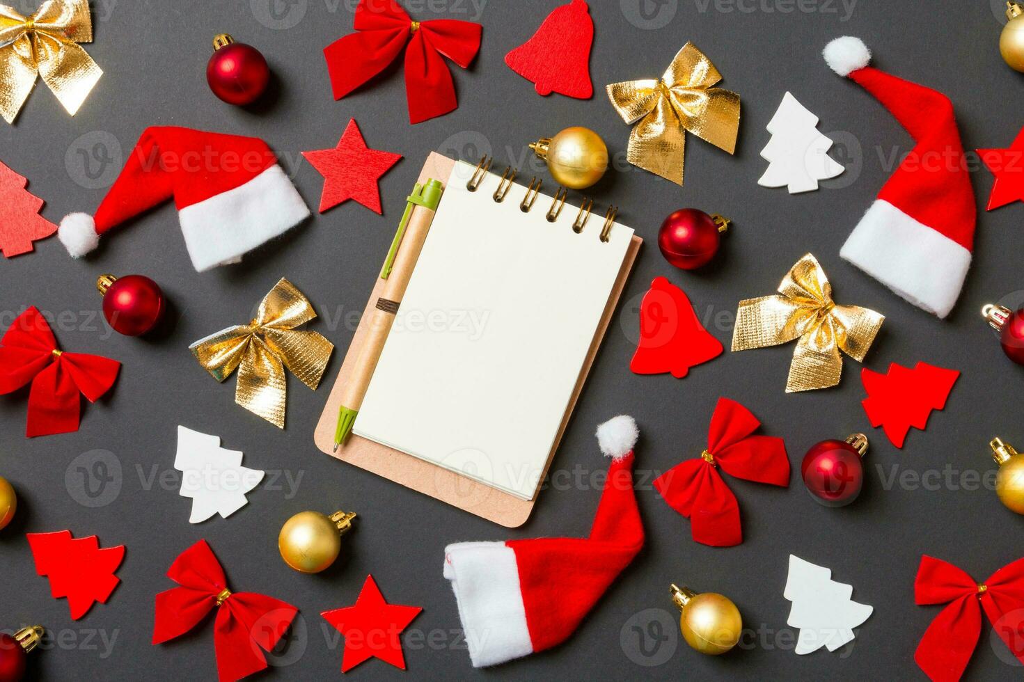 Top view of notebook on black background with New Year toys and decorations. Christmas time concept photo