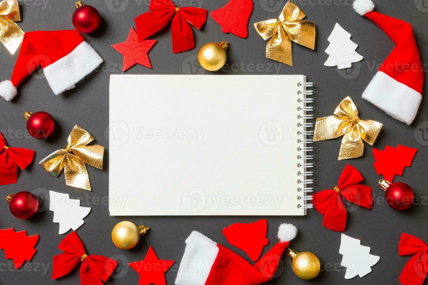 Top view of notebook on black background with New Year toys and decorations. Christmas time concept photo