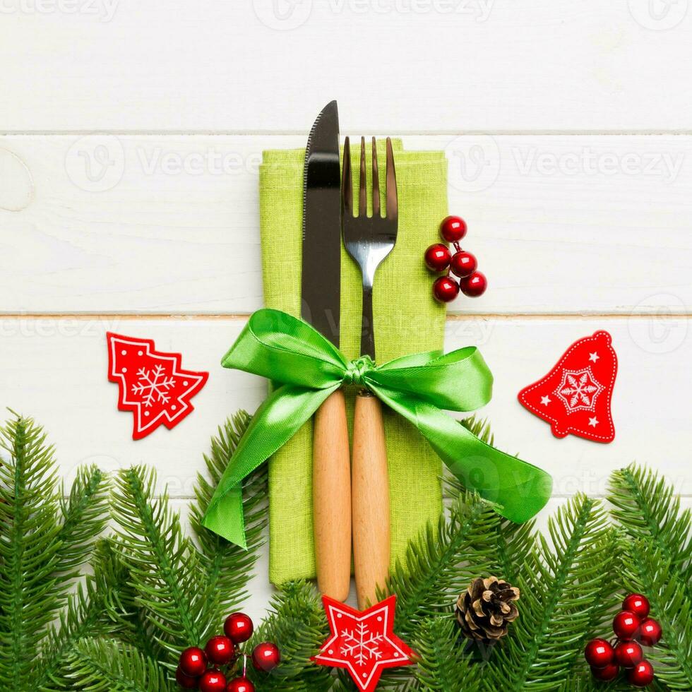 Top view of christmas decorations on wooden background. Fork and knife on napkin tied up with ribbon and empty space for your design. New year pattern concept photo