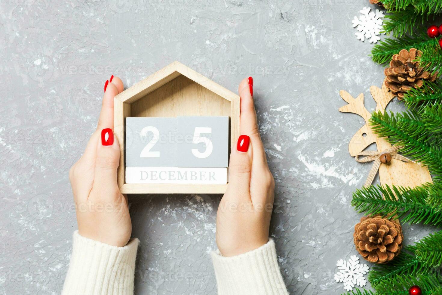 Top view of female hands holding a calendar on cement background. The twenty fifth of December. Holiday decorations. Christmas concept photo