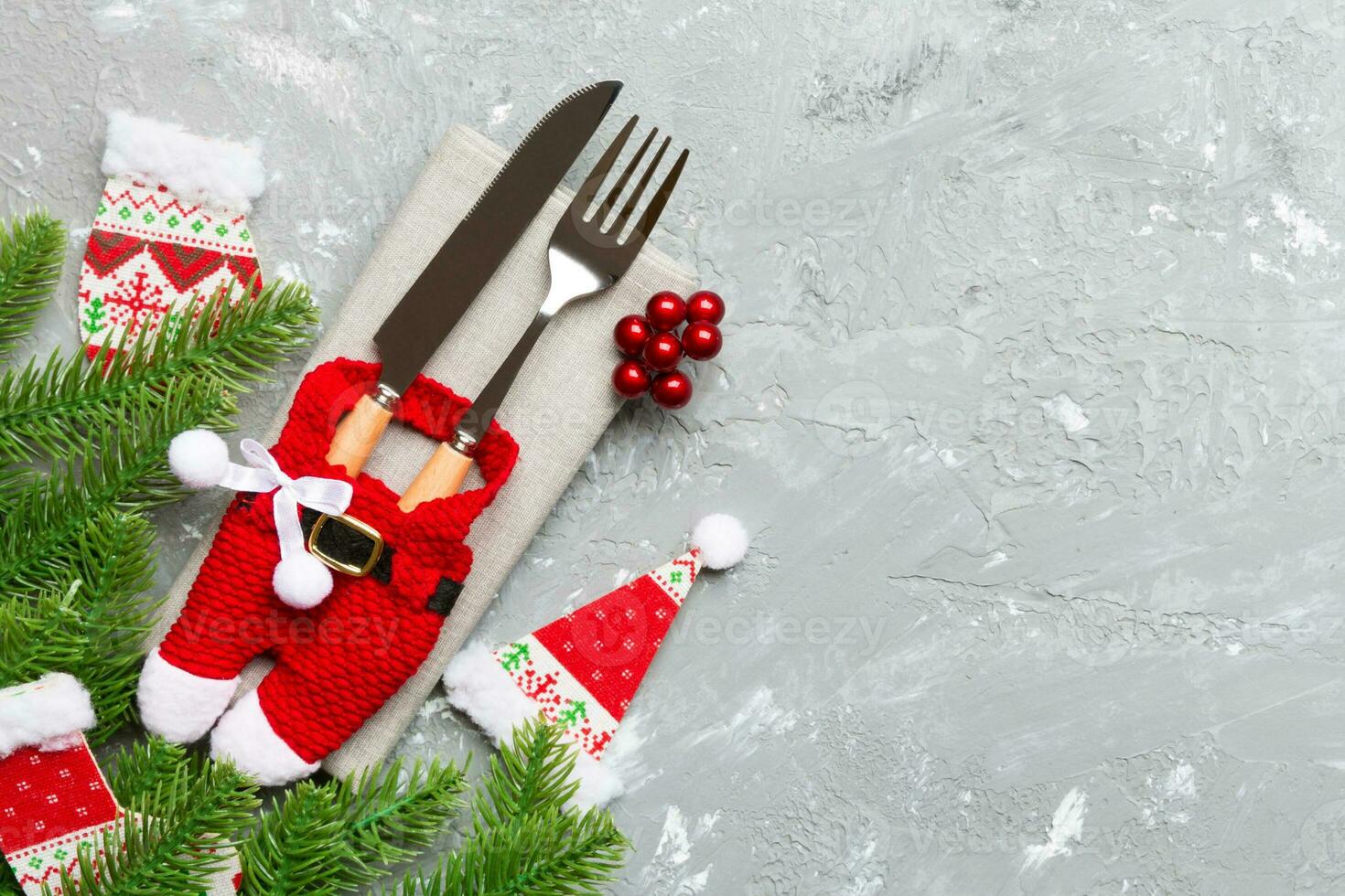 Top view of christmas decorations on cement background. Fork and knife on napkin tied up with ribbon and empty space for your design. New year pattern concept photo