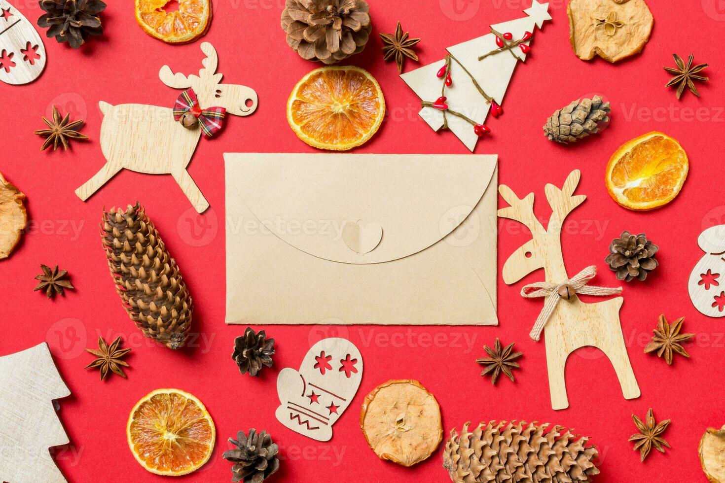 Top view of craft envelope, red background decorated with festive toys and Christmas symbols reindeers and New Year trees. Holiday concept photo