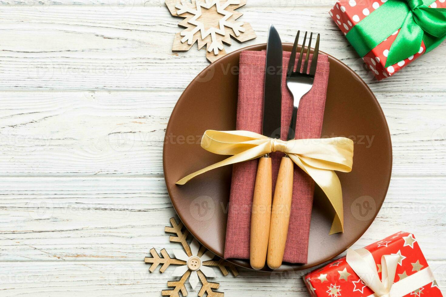 Top view of plate, fork and knife served on Christmas decorated wooden background. New Year Eve concept with copy space photo