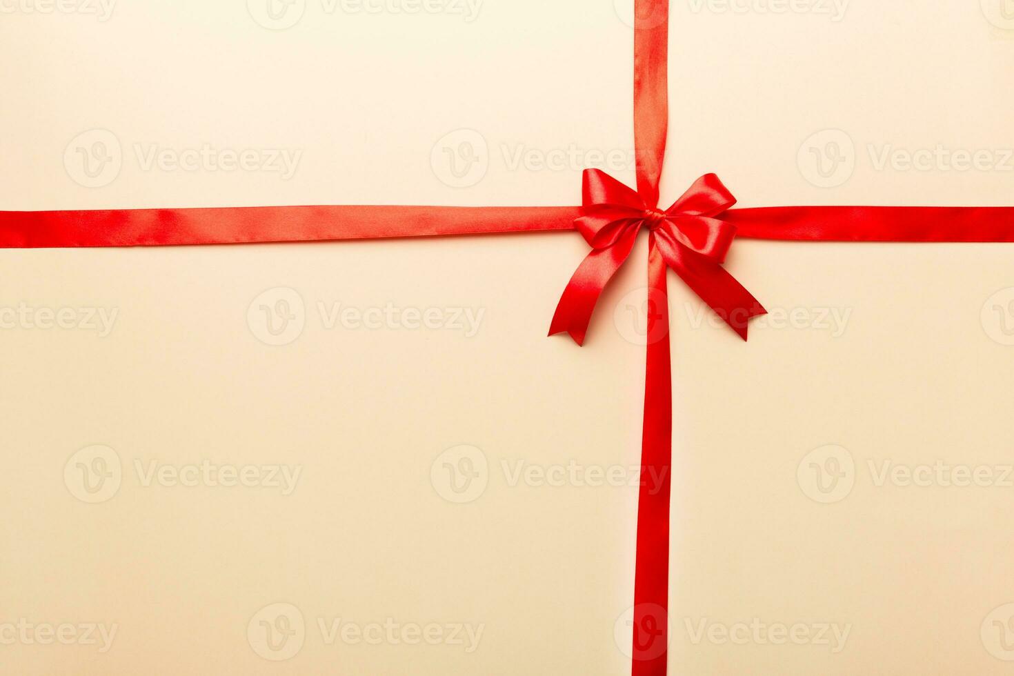 Top view of Red ribbon rolled and red bow isolated on colored background. Flat lay with copy space photo