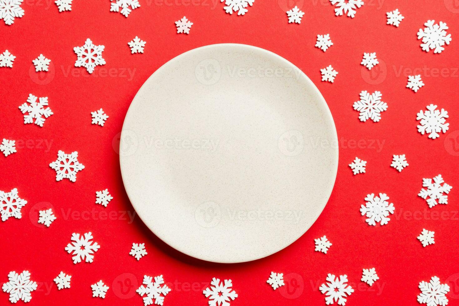 Top view of empty plate surrounded with snowflakes on colorful background. New Year dinner concept photo