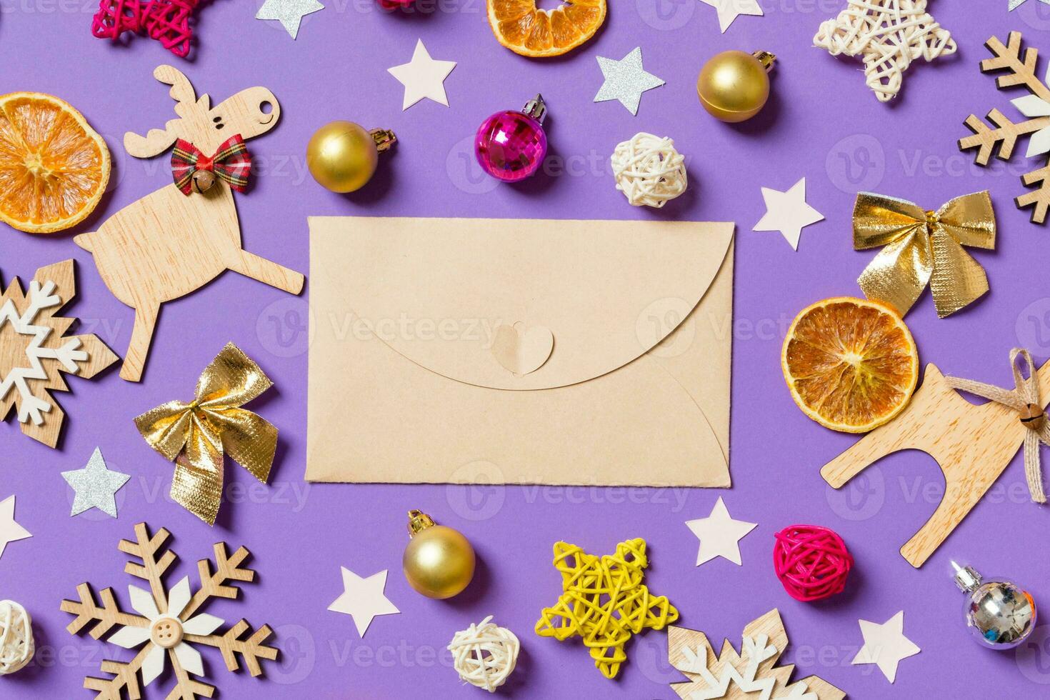 Top view of craft envelope surrounded with New Year toys and decorations on purple background. Christmas time concept photo