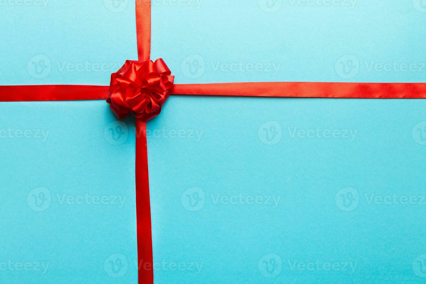 Top view of Red ribbon rolled and red bow isolated on colored background. Flat lay with copy space photo