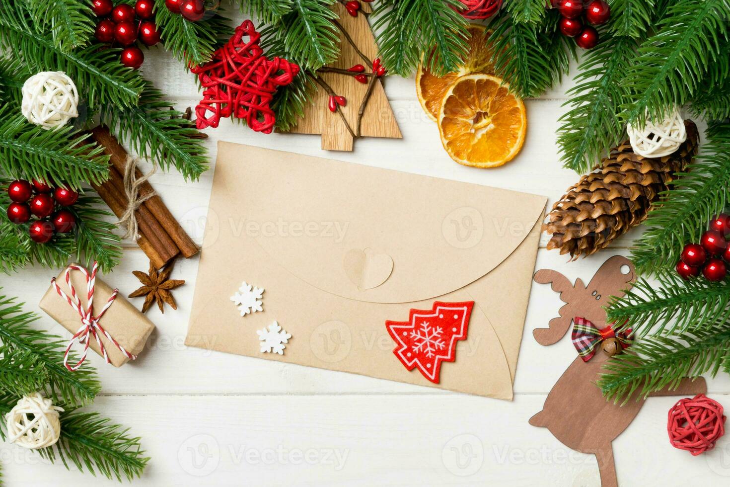 Top view of fir tree branches, envelope and festive decorative toys on wooden background. New Year time concept photo