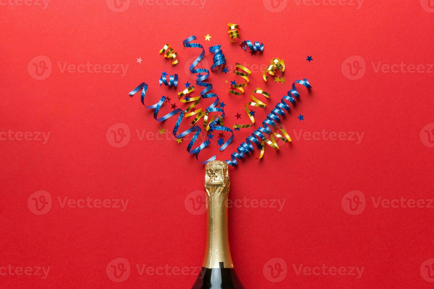 Creative flat lay composition with bottle of champagne and space for text on color background. Champagne bottle with colorful party streamers. holiday or christmas concept photo