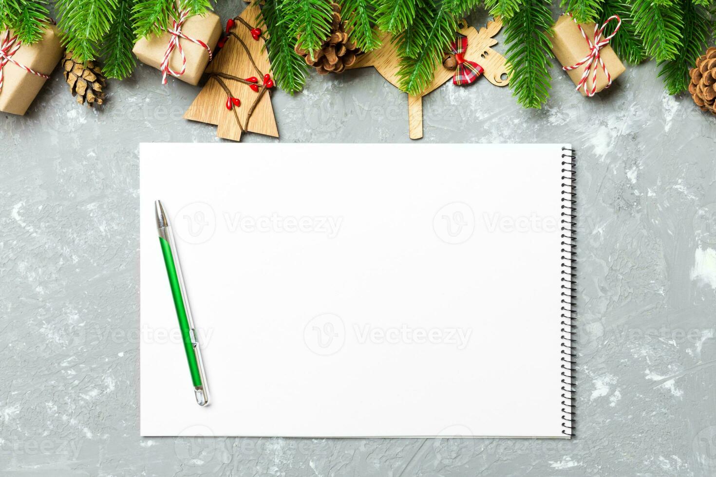 Top view of a notebook on cement holiday background made of fir tree and New Year decorations. Christmas time concept photo