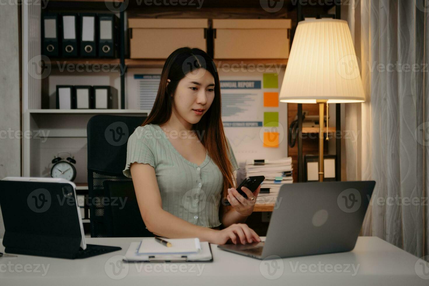 joven hermosa mujer trabajo tarde desde hogar en habitación a tarde noche horas extras.empresaria doblar terminado lugar de trabajo mientras mirando a ordenador portátil computadora. foto