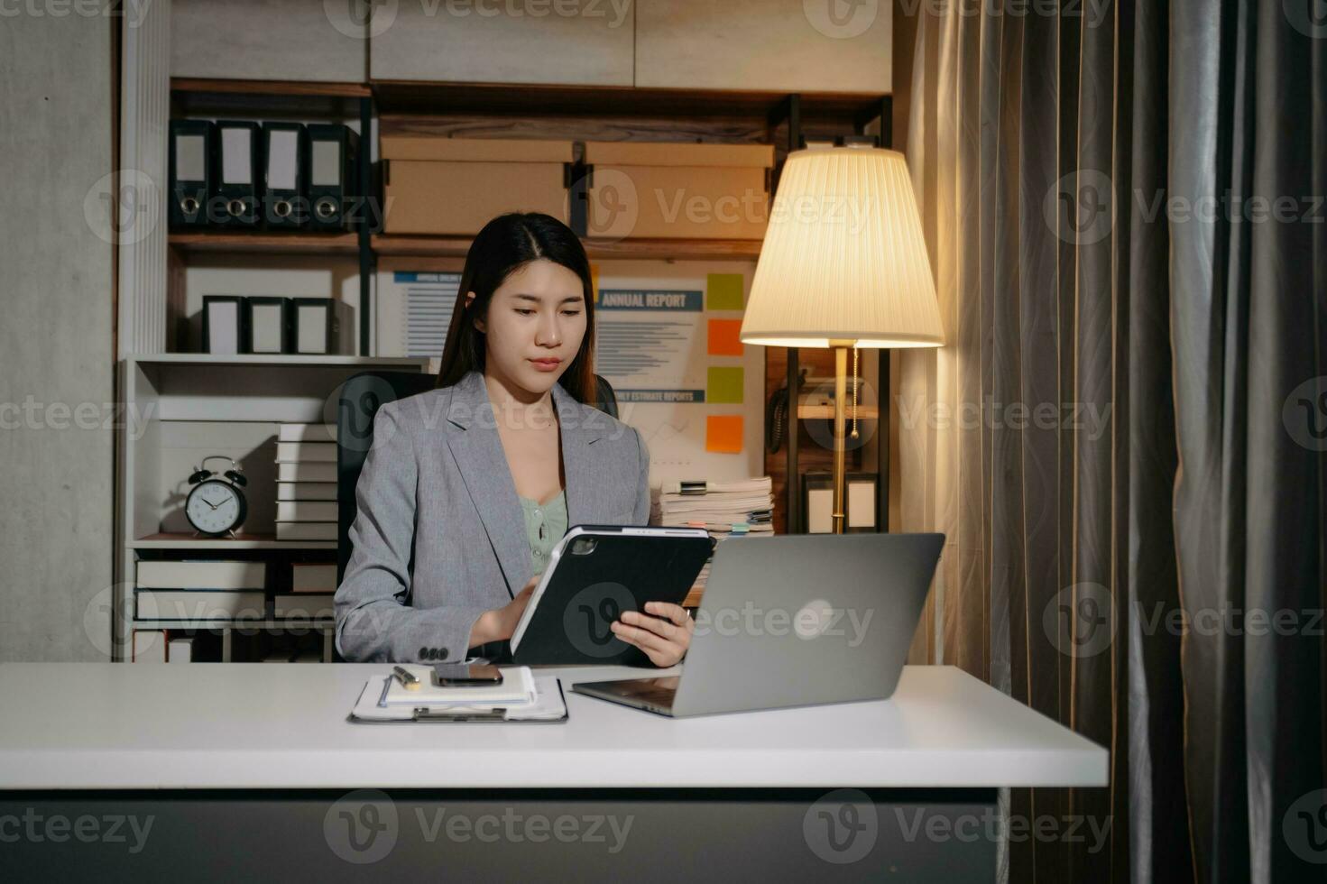 Young beautiful woman work late from home in room at late night overtime.Businesswoman bending over workplace while looking at laptop computer. photo