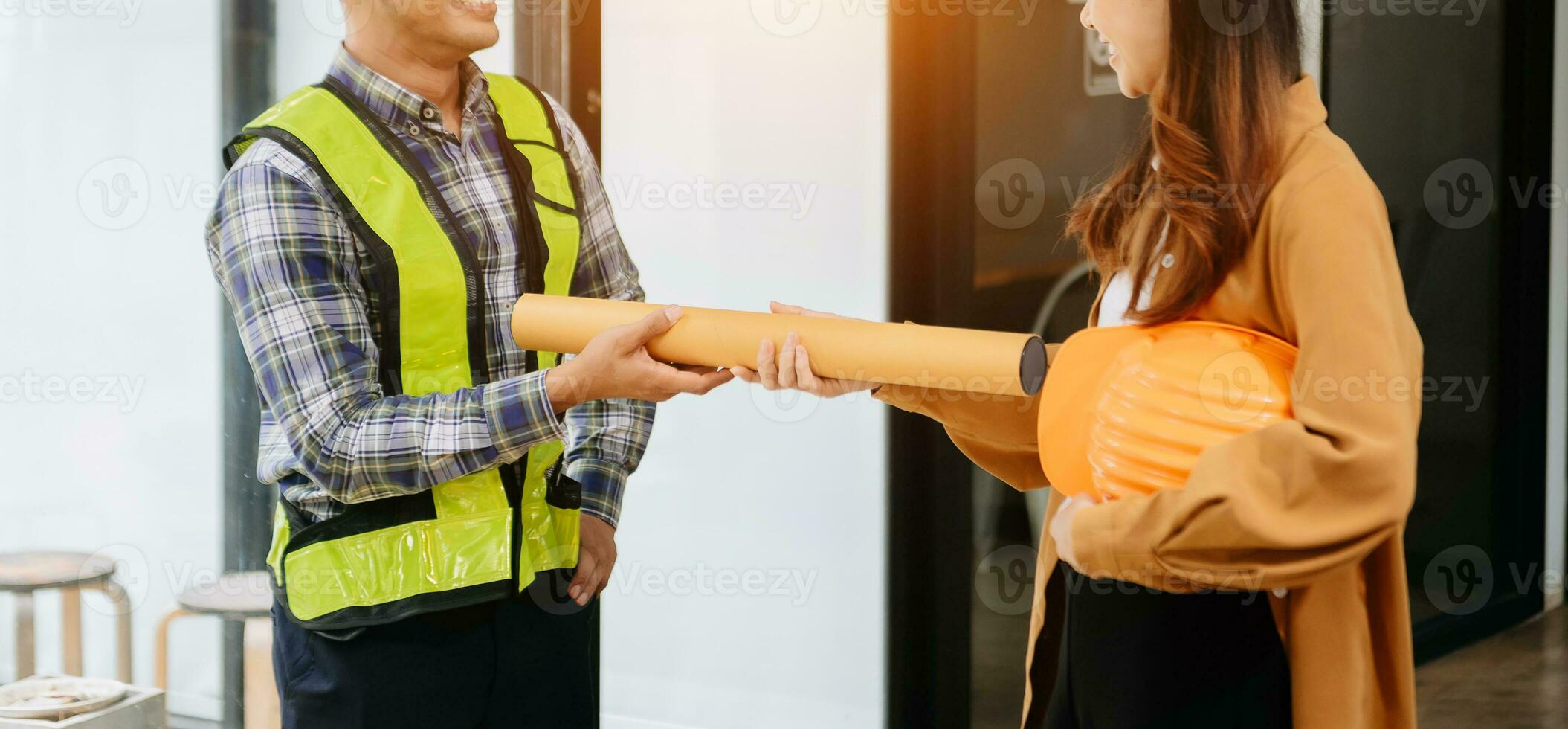 Construction team shake hands greeting start new project plan behind yellow helmet on desk in office center to consults about their building project. photo