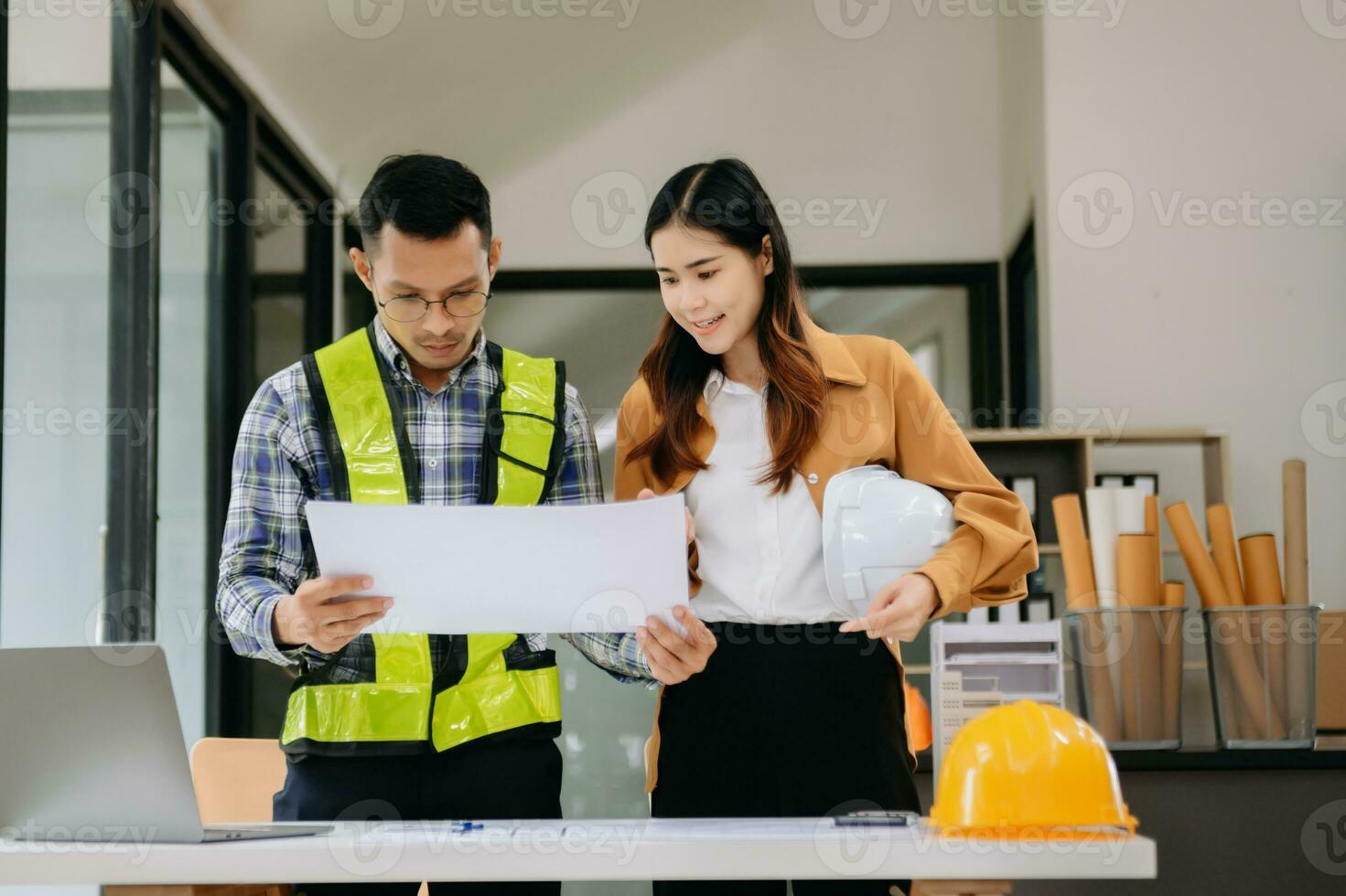 Engineer teams meeting working together wear worker helmets hardhat with on architectural project site and making model house. Asian industry professional team in modern office photo