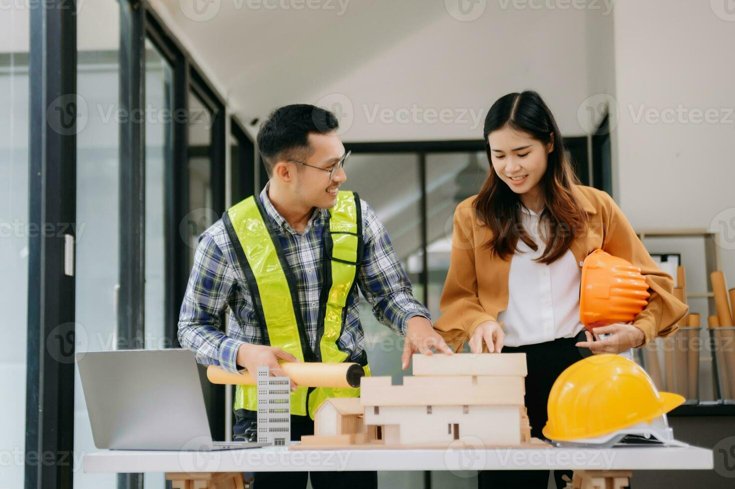 Engineer teams meeting working together wear worker helmets hardhat with on architectural project site and making model house. Asian industry professional team in modern office photo