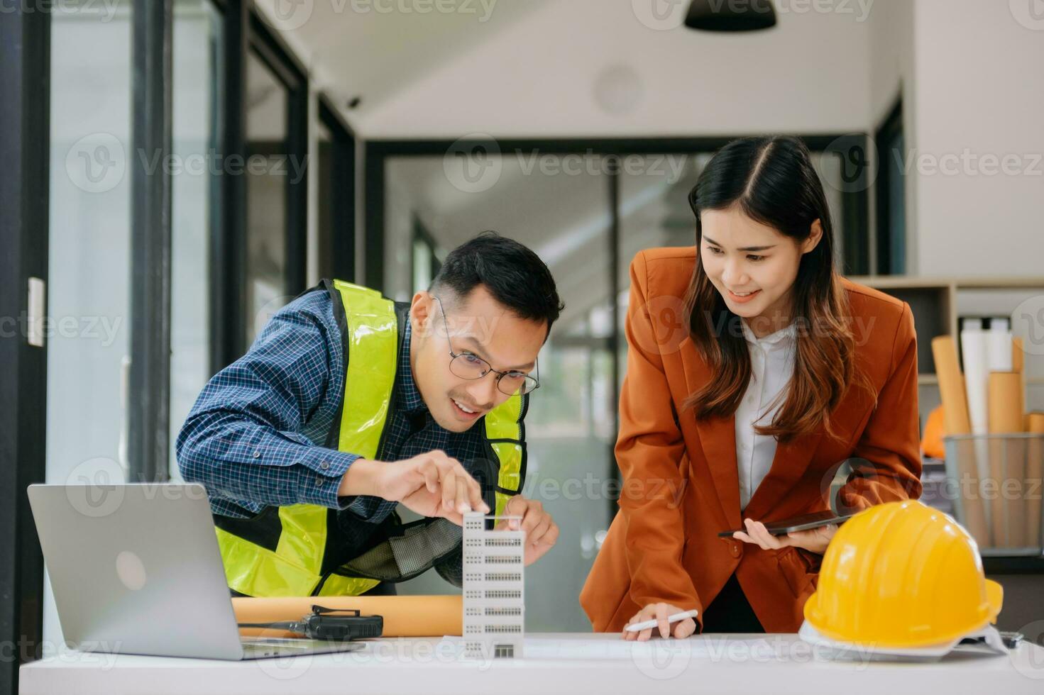 Engineer teams meeting working together wear worker helmets hardhat with on architectural project site and making model house. Asian industry professional team in modern office photo