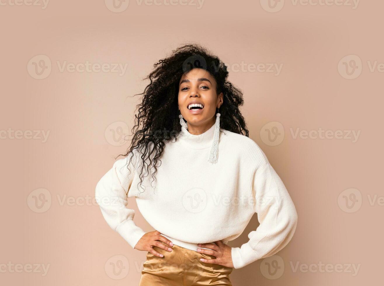 Laughing black woman in casual outfit  . Studio shot of smiling stylish african american girl  posing  on  beige background. photo