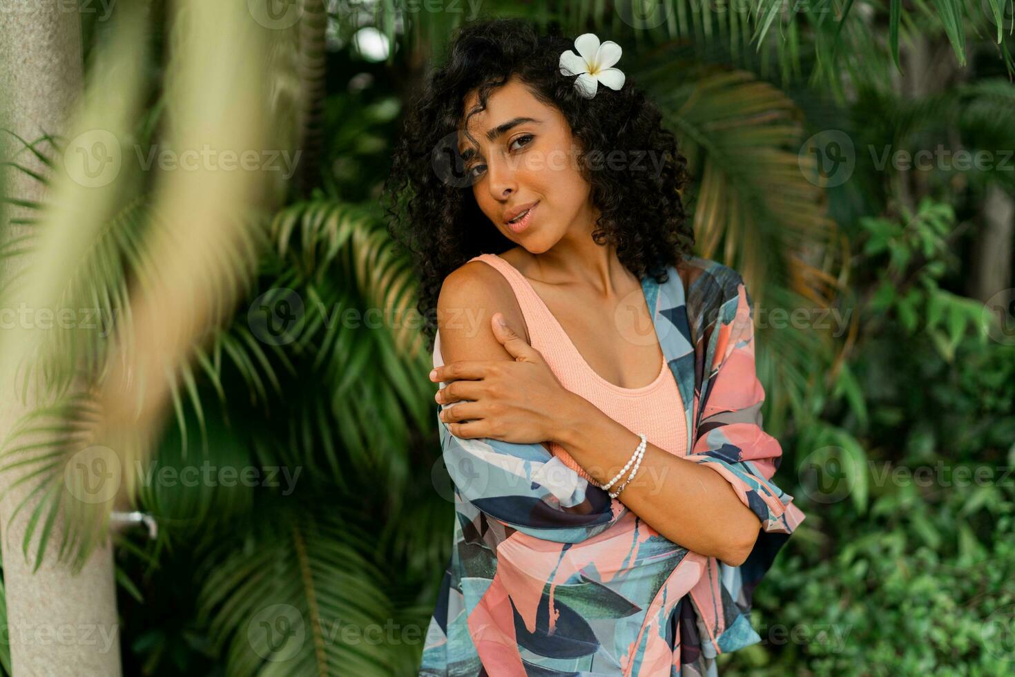 Close up portrait of  smiling woman with  plumeria flower in hairs after spa in   luxury resort. Wearing boho tropical outfit. photo