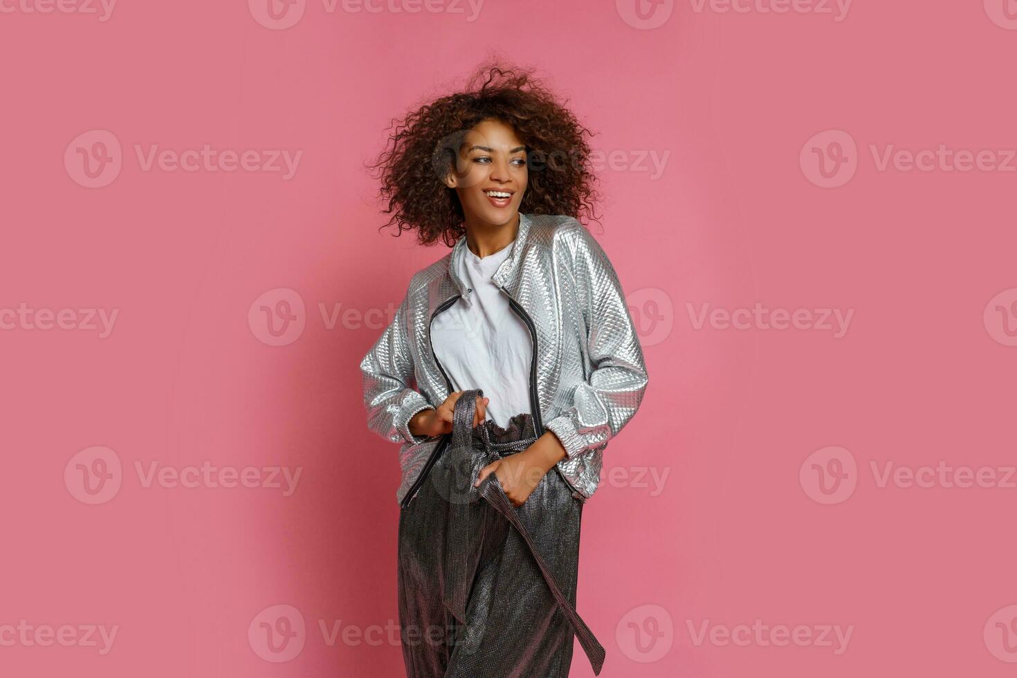 pretty mix race woman with  curly Afro hairs posing on pink background. photo