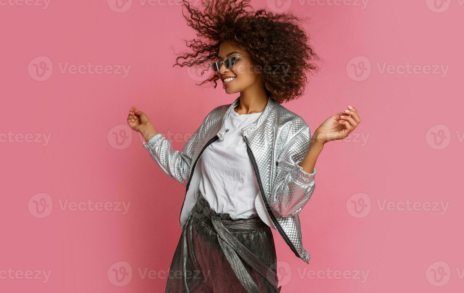 pretty mix race woman with  curly Afro hairs posing on pink background. photo