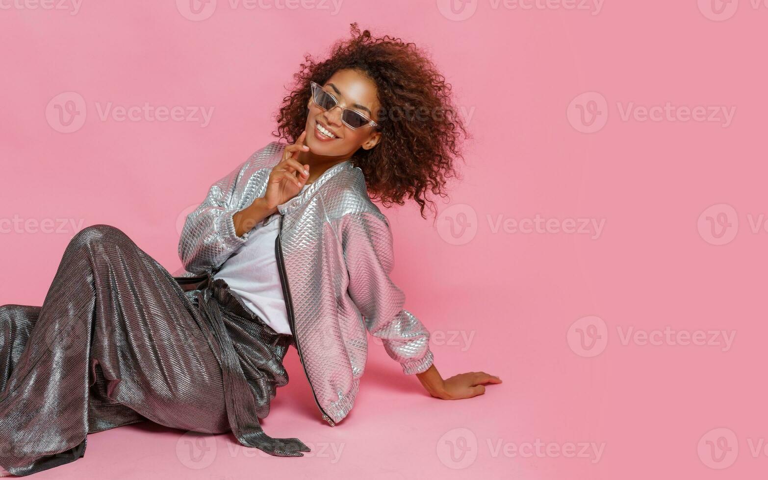 pretty mix race woman with  curly Afro hairs posing on pink background. photo