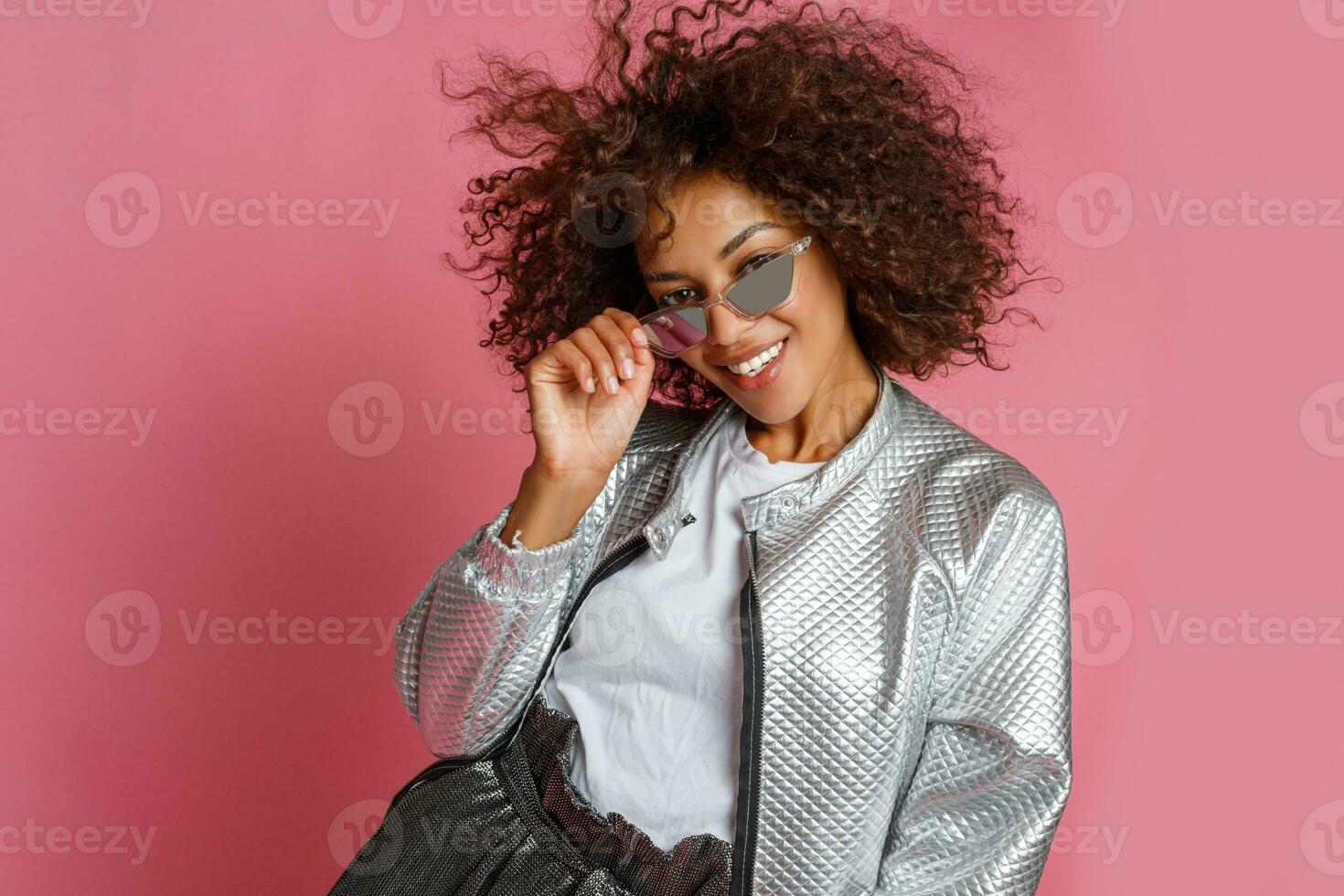 pretty mix race woman with  curly Afro hairs posing on pink background. photo