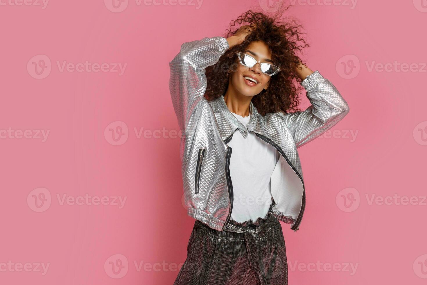 pretty mix race woman with  curly Afro hairs posing on pink background. photo