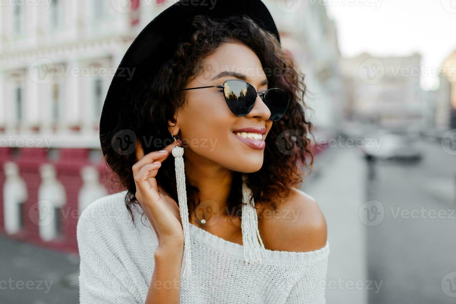 Sensual african lady in trendy  outfit enjoying good day on photoshoot. Perfect candid smile, white teeth. Black hat. photo