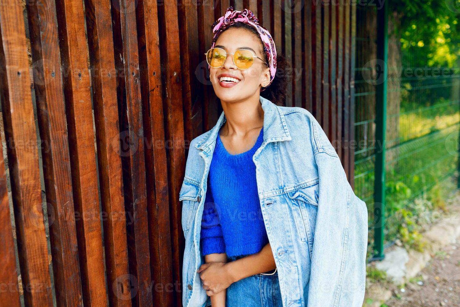 Happy  hipster mixed girl with perfect whit teeth spending great time outdoor . Trendy jeans jacket. photo