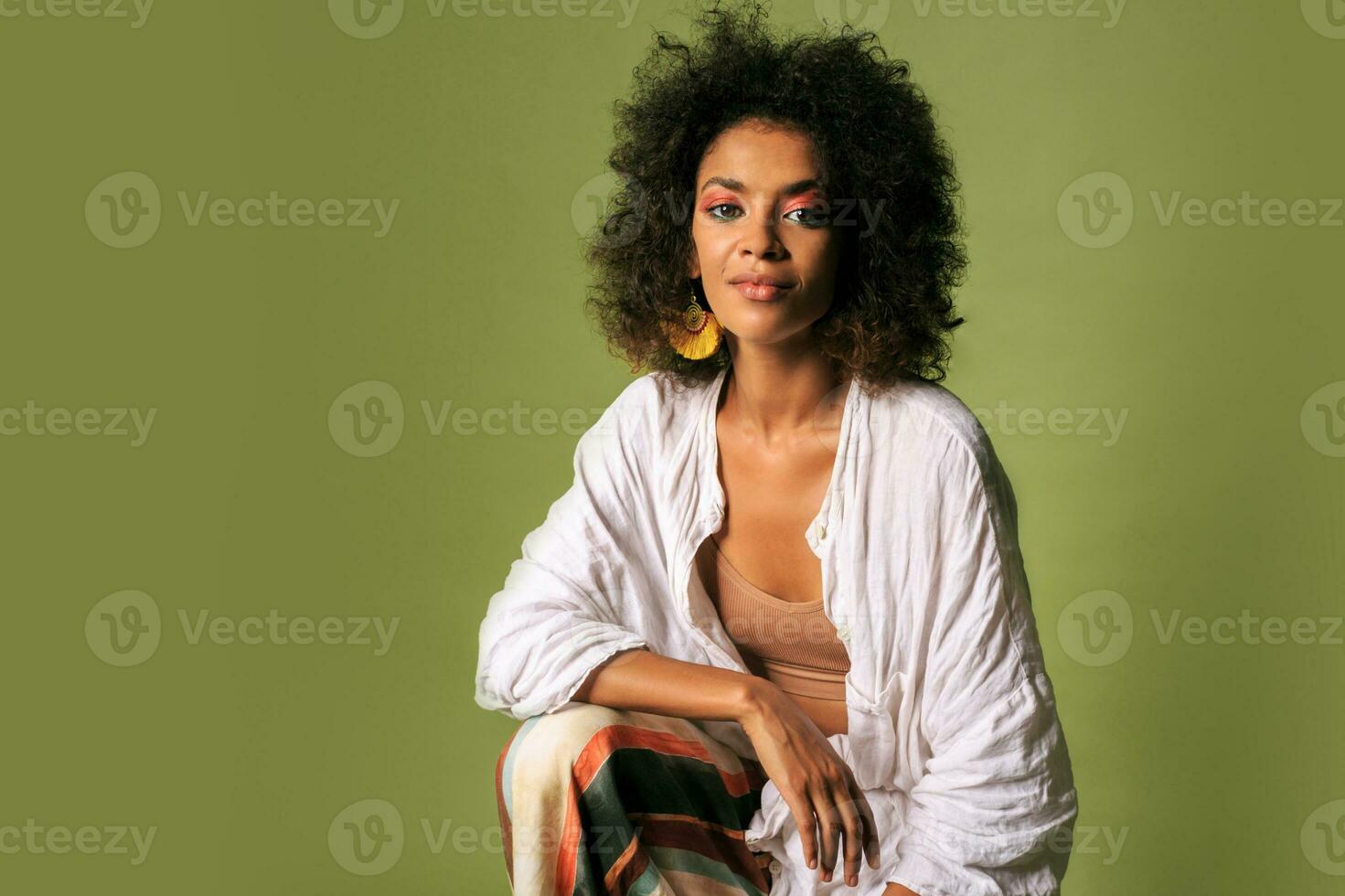 Fashionable african woman in stylish summer outfit posing over green background in studio. photo